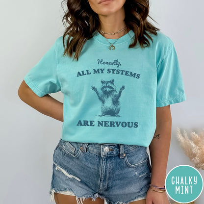 Comfort Colors tee in Chalky Mint featuring graphic illustration of a nervous raccoon with arms raised in air