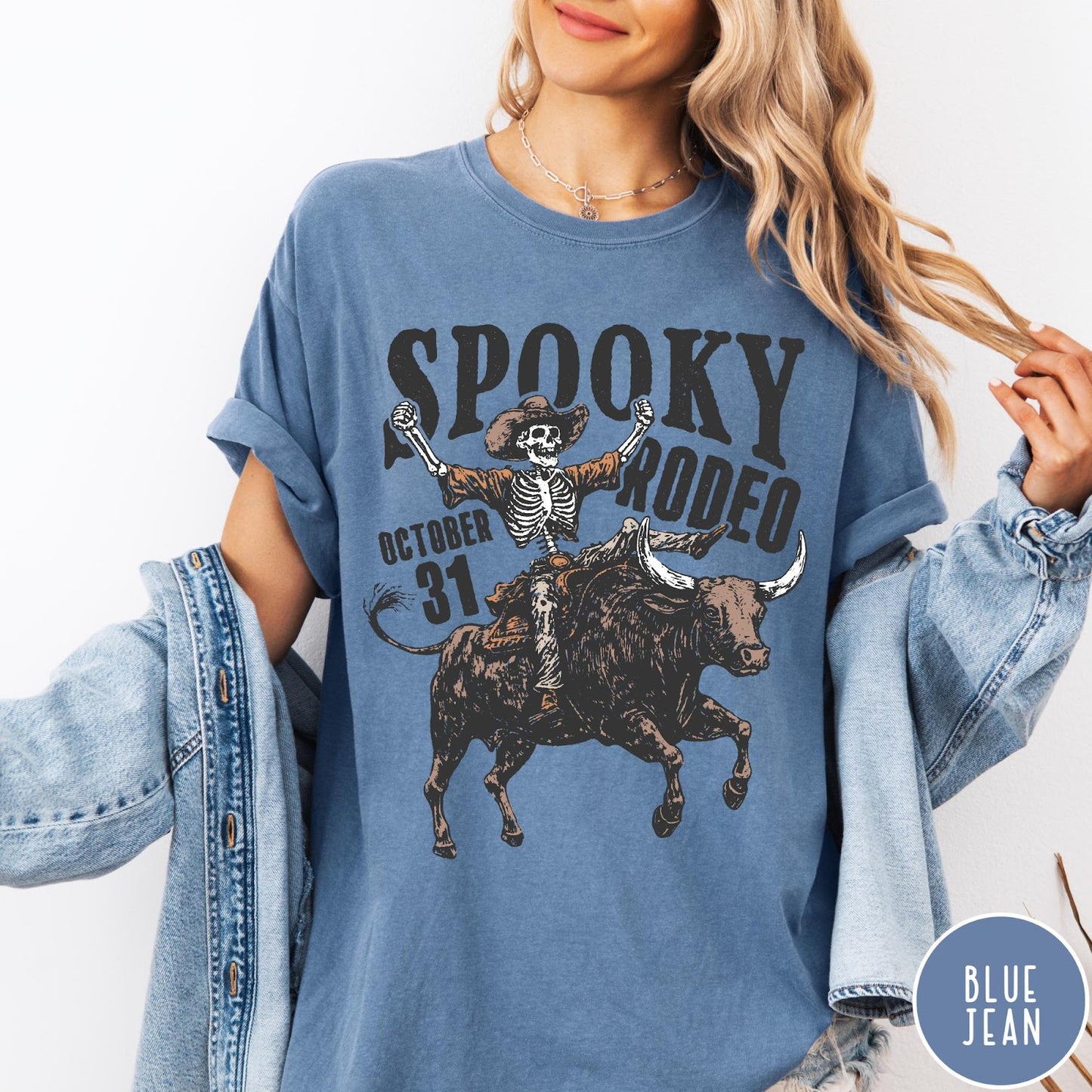 Comfort Colors tee in Blue Jean featuring western style graphic of a skeleton cowboy riding a bucking bull