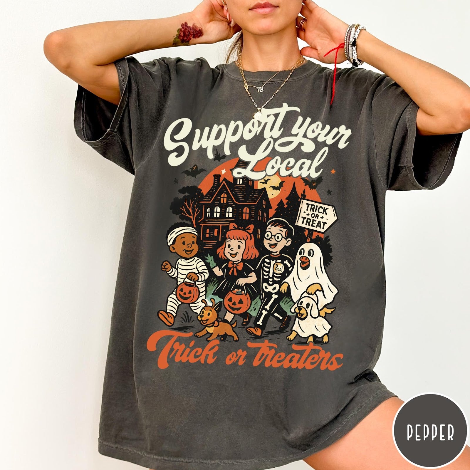 Comfort Colors tee in Pepper featuring vintage style trick or treaters graphic with a haunted house background