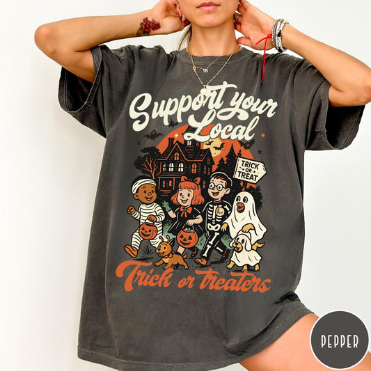 Comfort Colors tee in Pepper featuring vintage style trick or treaters graphic with a haunted house background