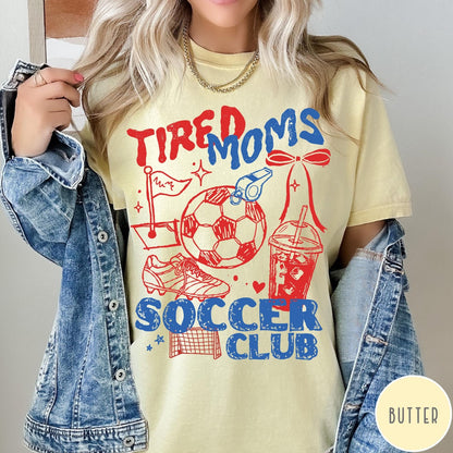 Comfort Colors tee in Butter featuring soccer mom life graphic with soccer ball, whistle, and iced coffee